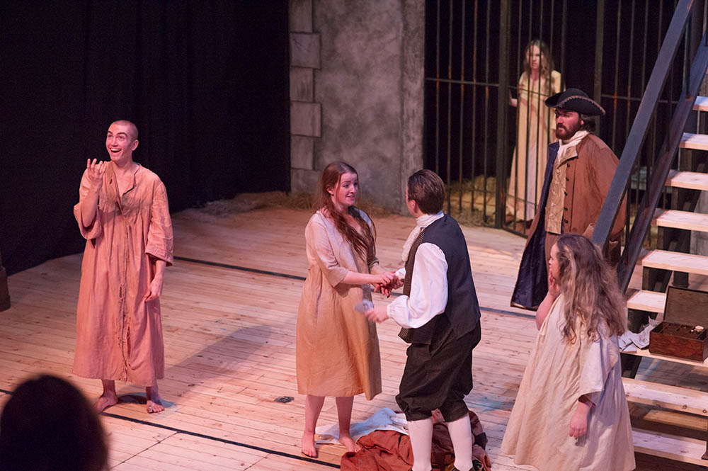 Actors in prison scene – woman holding a mans hand